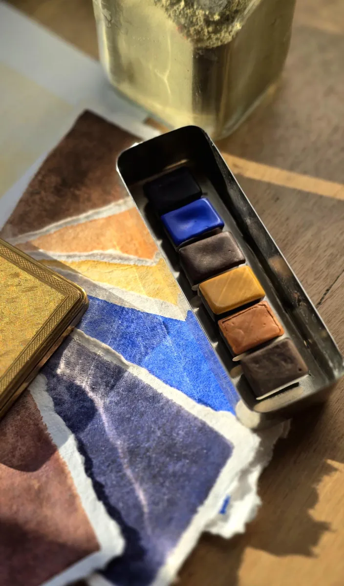 Gros plan sur les 6 demi-godets d'aquarelle artisanale dans l'ancienne boîte d'infirmière